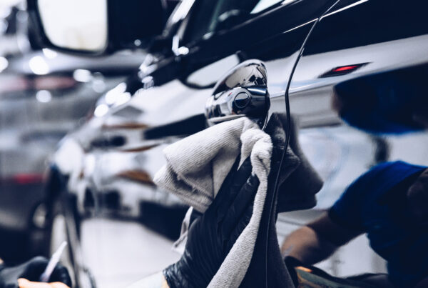 Man worker in car wash polishing car with cloth. Car detailing